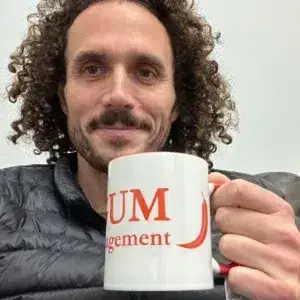 White ceramic coffee mug with the red Red Gum Property Management logo, held in hand