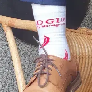 White crew socks with the red Red Gum Property Management logo, worn with tan leather brogues